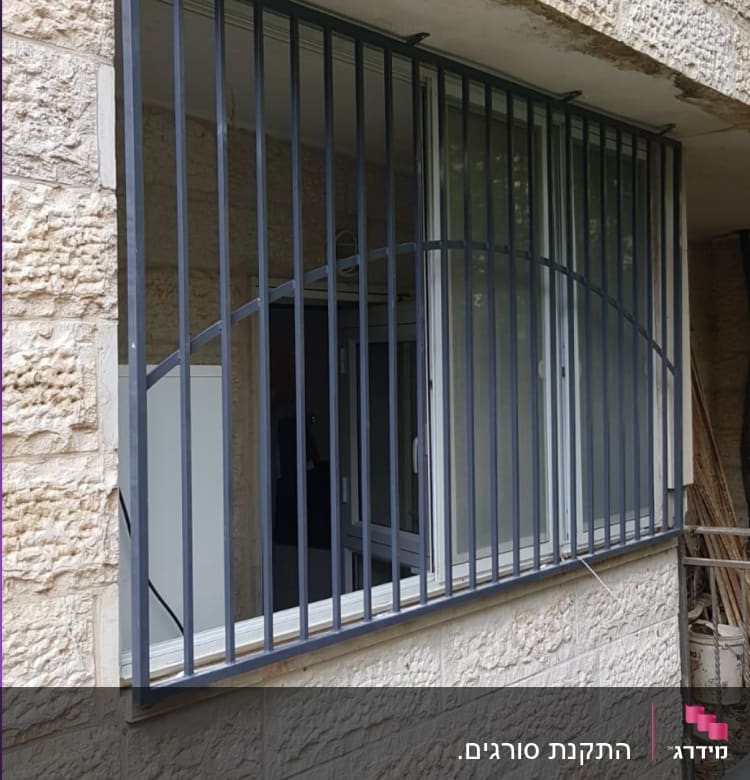 חלון עם סורגים מתכתיים על קיר אבן